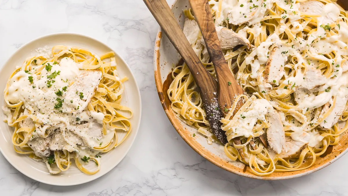Fettuccine Alfredo with grilled chicken in a bowl and on a plate.