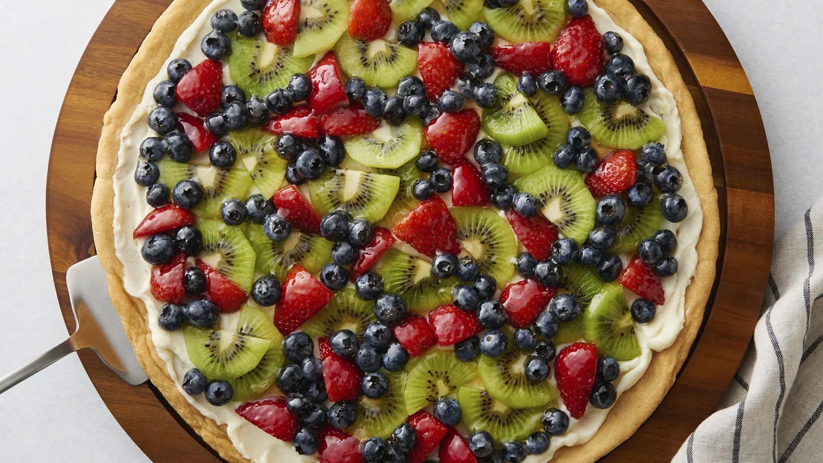 Fruit pizza made with sugar cookie dough topped with kiwi and berries.