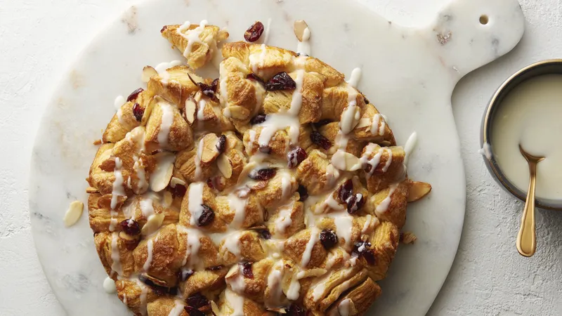 A delicious Cranberry Orange Pull-Apart Bread, topped with cranberry and white icing, presented on a white plate.
