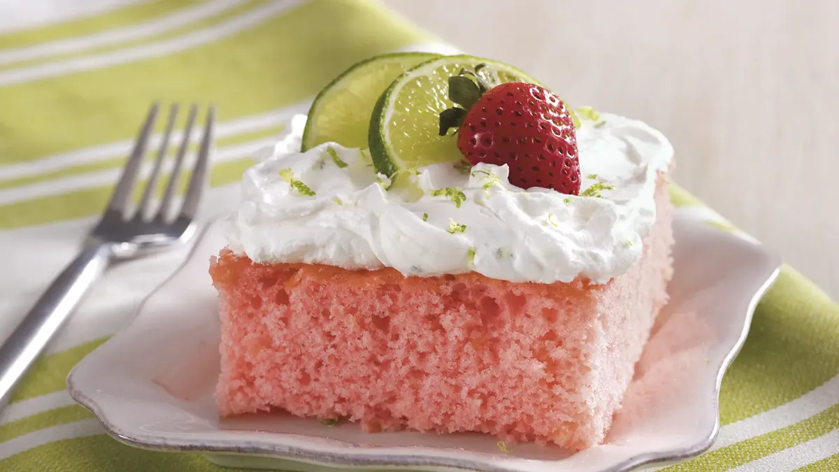 Strawberry Margarita Cake. Pink sheet cake with white frosting topped with strawberries and sliced limes.