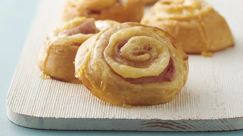 Ham and cheese pinwheels on a wooden board.