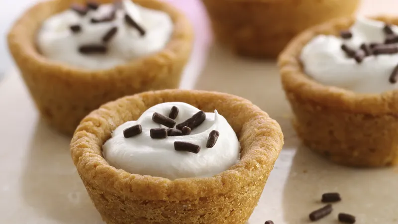 Four delightful peanut butter cream cups filled with white cream and topped with chocolate sprinkles, all elegantly presented on a light surface.