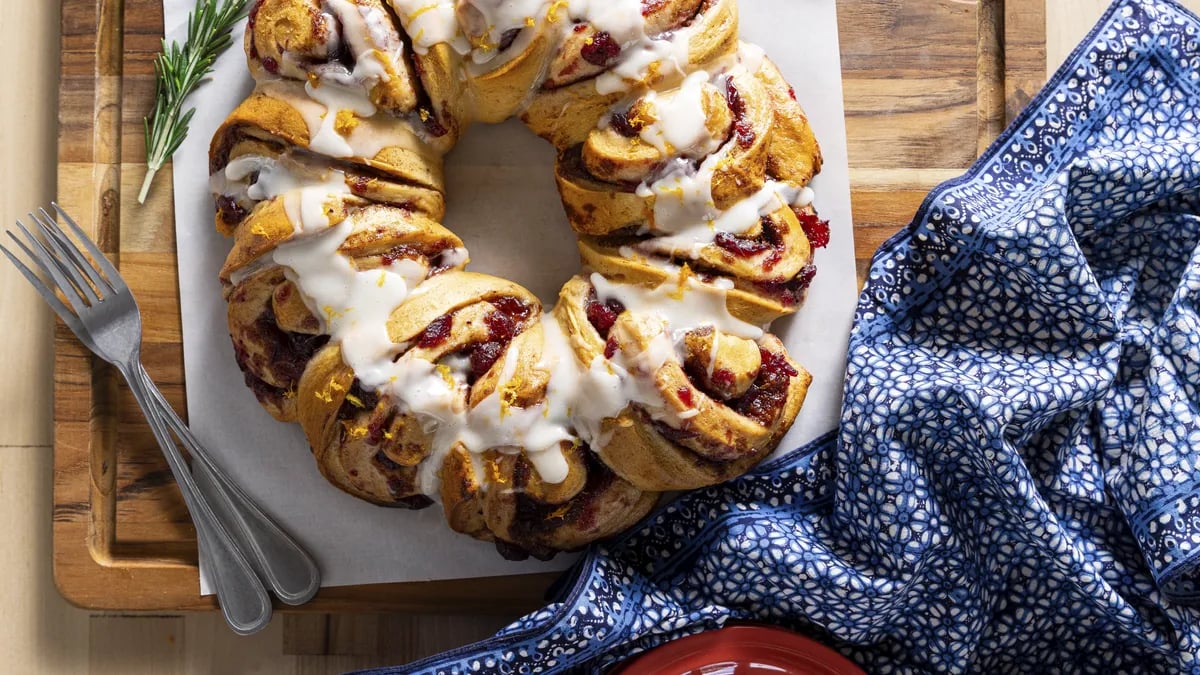 Cranberry cinnamon roll wreath drizzled with icing.