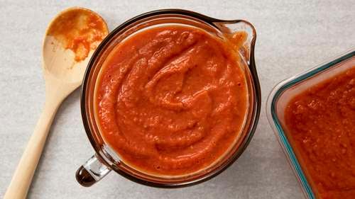 salsa maker squeezes tomatoes to produce traditional home-made sauce