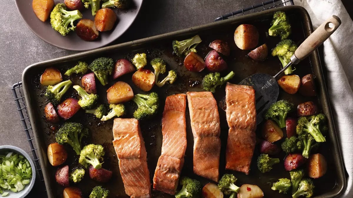 Roasted salmon filets broccoli and red potatoes on a sheet pan.