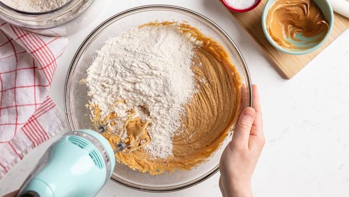 Measuring cups of flour and sugar with a peanut butter mixture in